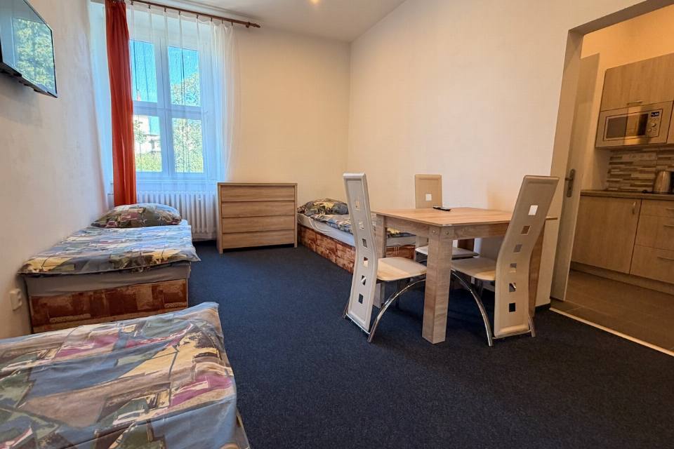 Apartmán č. 2 — lůžka, jídelní stůl a vstup do kuchyňky