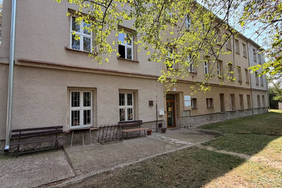 Vstup do budovy ubytovny s lavičkami před vchodem