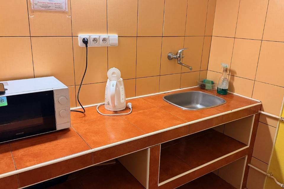 Společná kuchyňka na patře s mikrovlnnou troubou, konvicí a dřezem
